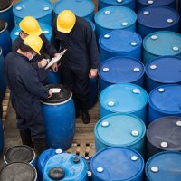 Group of men working at a chemical warehouse classifying barrels